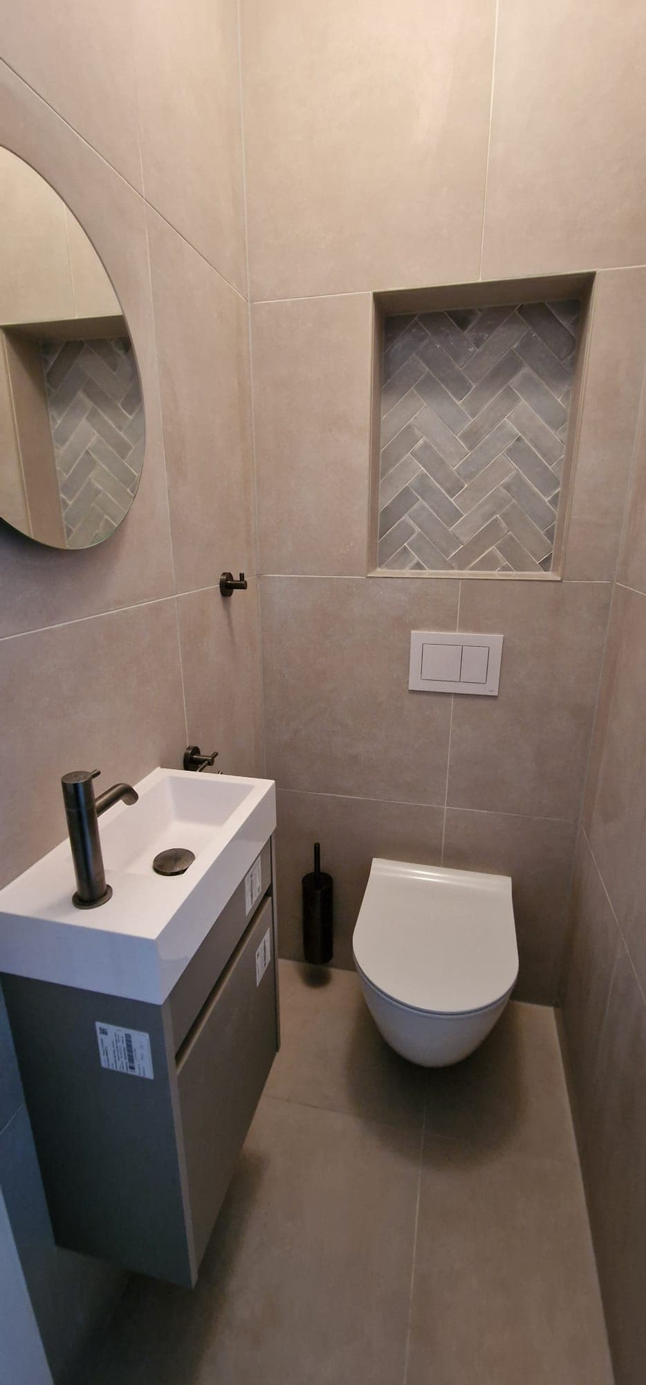 Beige toiletruimte met visgraat tegelnis en kleine wastafel